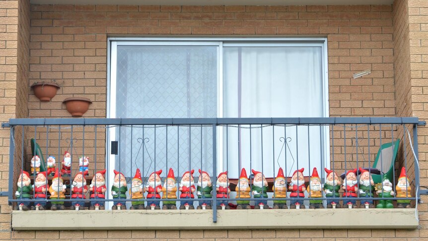 A gathering of gnomes line up along the balcony of a flat.