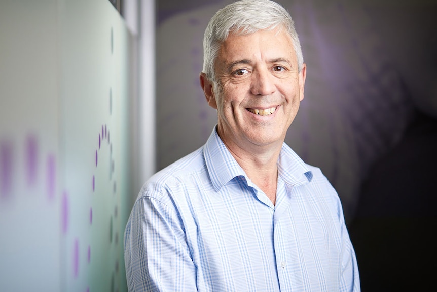 A man in a business shirt smiles for a portrait.