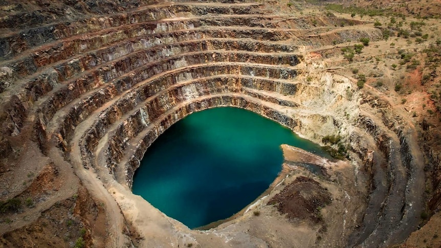 A blue body of water at the bottom of a mining pit or spiral