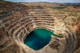 A blue body of water at the bottom of a mining pit or spiral