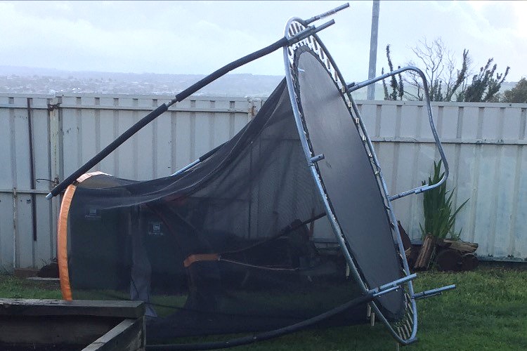 A trampoline on its side in a suburban backyard