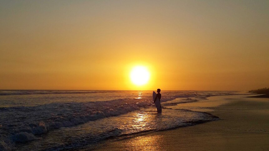 A surfer eyes the break at sunset at Playa el Paredon, Guatemala.