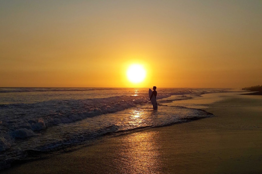 A surfer eyes the break at sunset at Playa el Paredon, Guatemala.