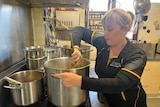 A woman stirs a giant pot of soup