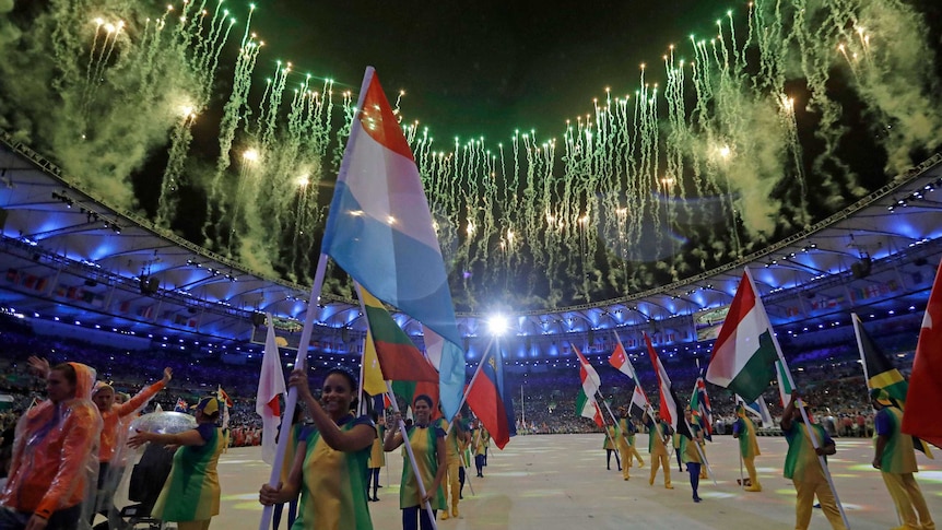 Fireworks go off as the flags are carried in during the Olympic closing ceremony.