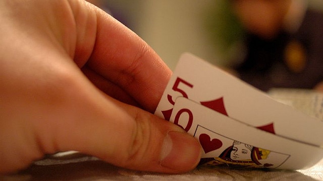 Generic picture of a poker player with a 5 of diamonds and queen of hearts.