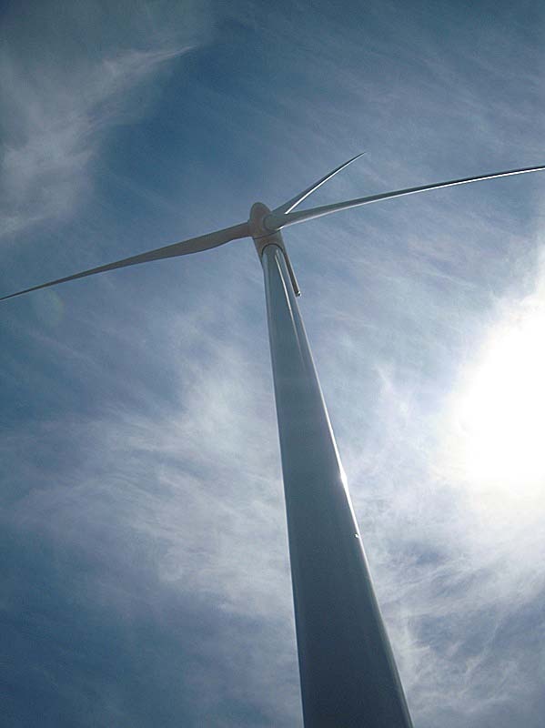 Looking up at a wind farm turbine.