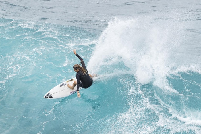A woman surfs on a white board in a black top