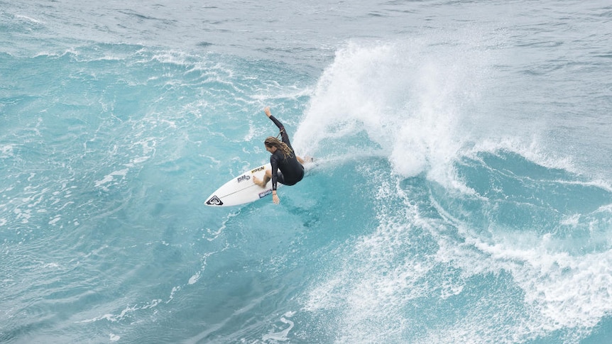 A woman surfs on a white board in a black top