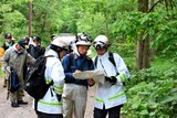 People in searching gear look at map in forest