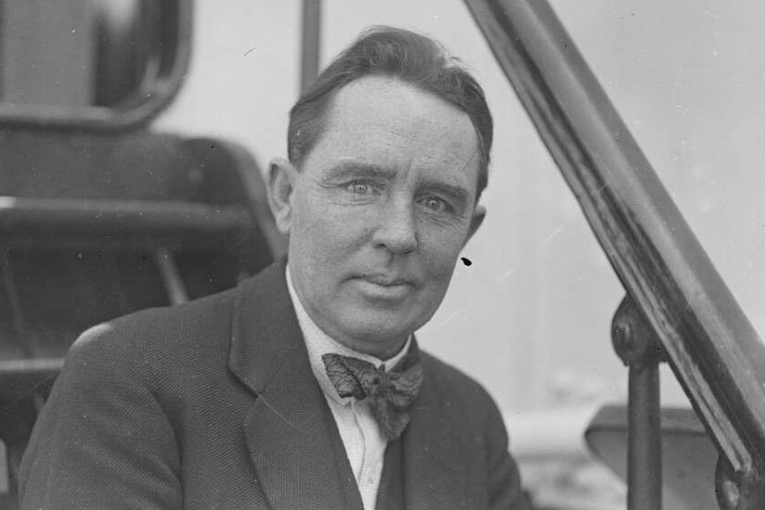 Black and white photo of a middle aged man in a suit wearnig a bow tie