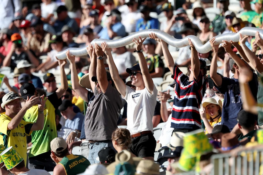 Cricket fans at a ODI between Australia and England at Perth STadium hold up a beer snake above their heads.