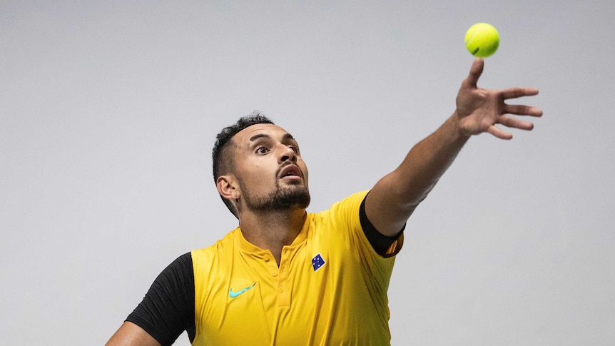 Nick Kyrgios throws the ball up as he prepares to serve.
