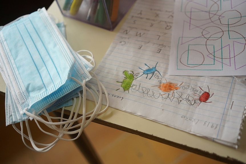 Face masks and classwork are seen on the desk of a student at Escuela 30.