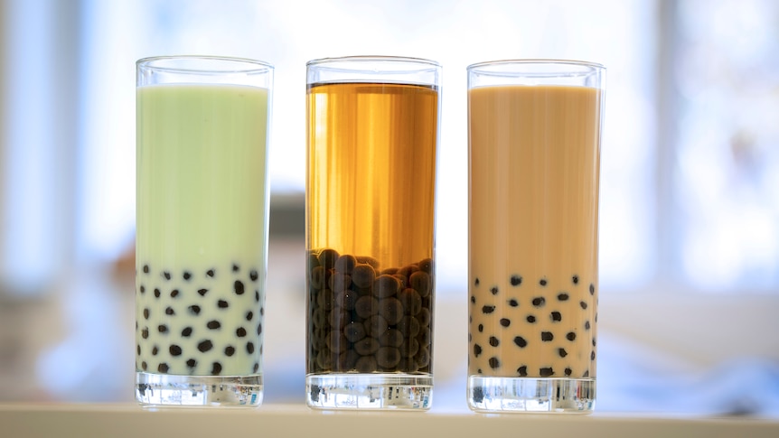 Close up of three glasses with colourful liquid inside them