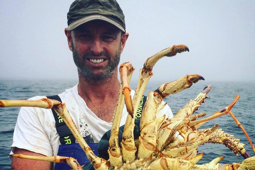 Commercial Fisherman Jason Moyce is pictured holding a large crustacean whilst on a boat