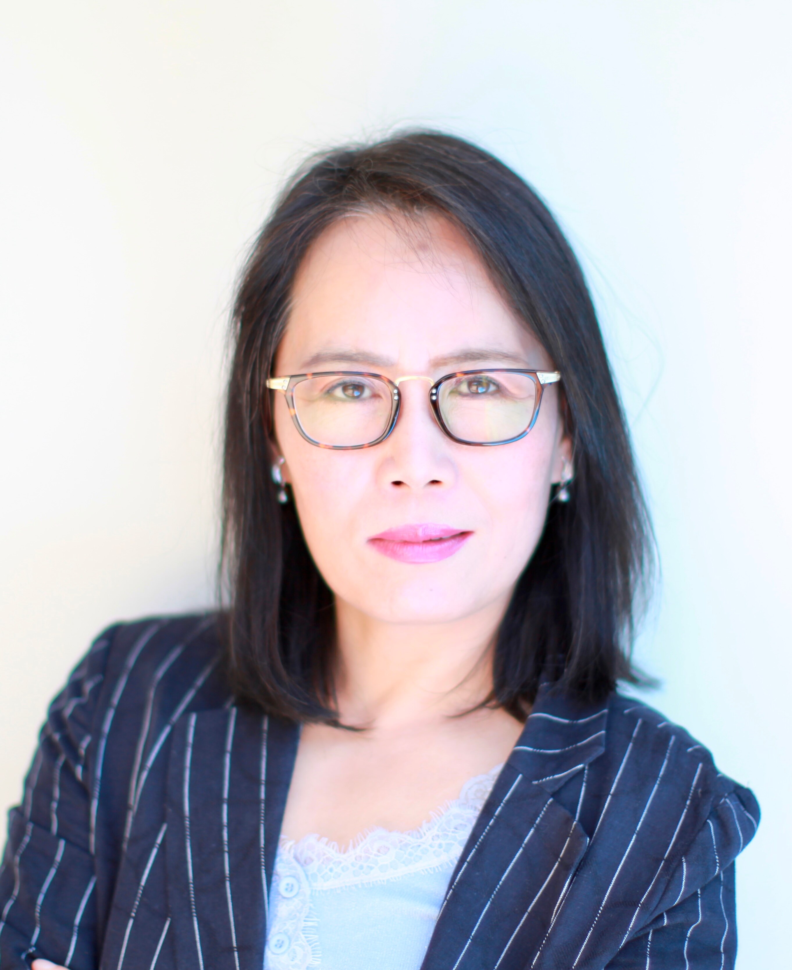 A woman wearing glasses looks at the camera.