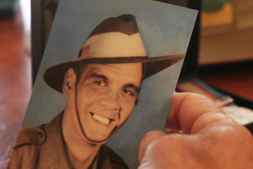 A photo of Darren holding a photo of his granpa Harold in army uniform