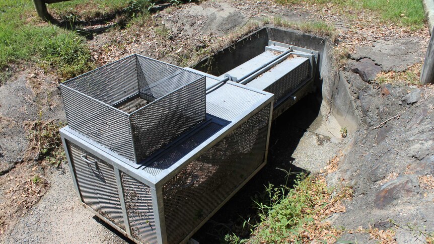 A large metal trap attached to a drain