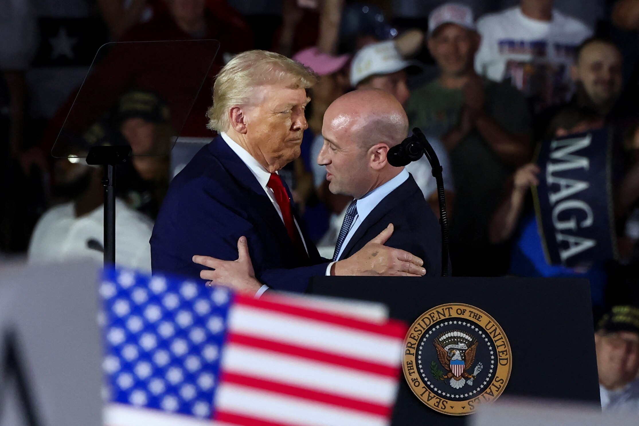 Trump and Stephen Miller hugging on stage during a rally.