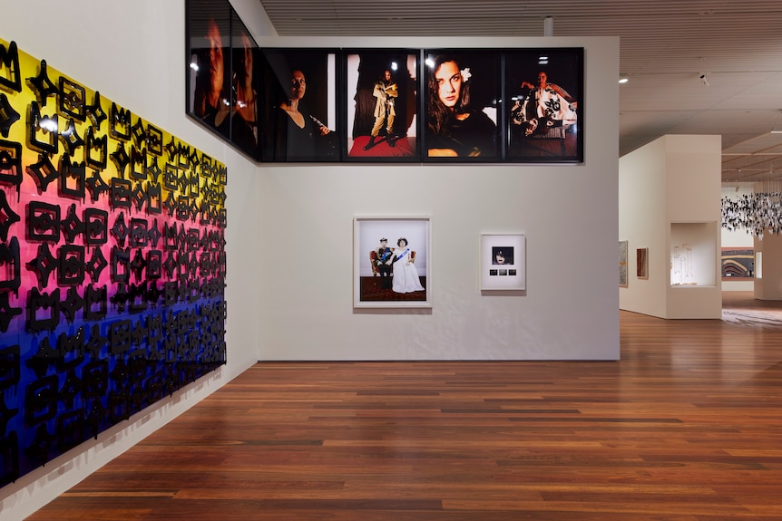 Four artworks in a gallery: a painting (left) and a series of large photographic portraits and two smaller artworks in front