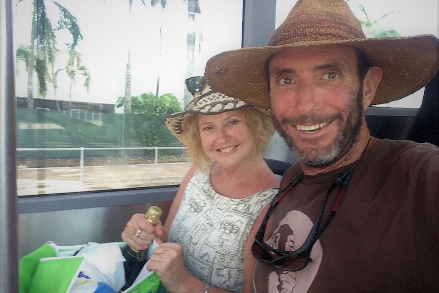Selfie of a smiling couple on a bus with an unopened champagne bottle in a bag.