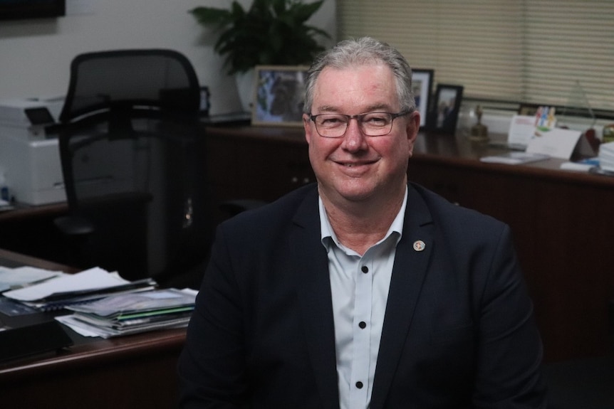 A man sits smiling in an office.