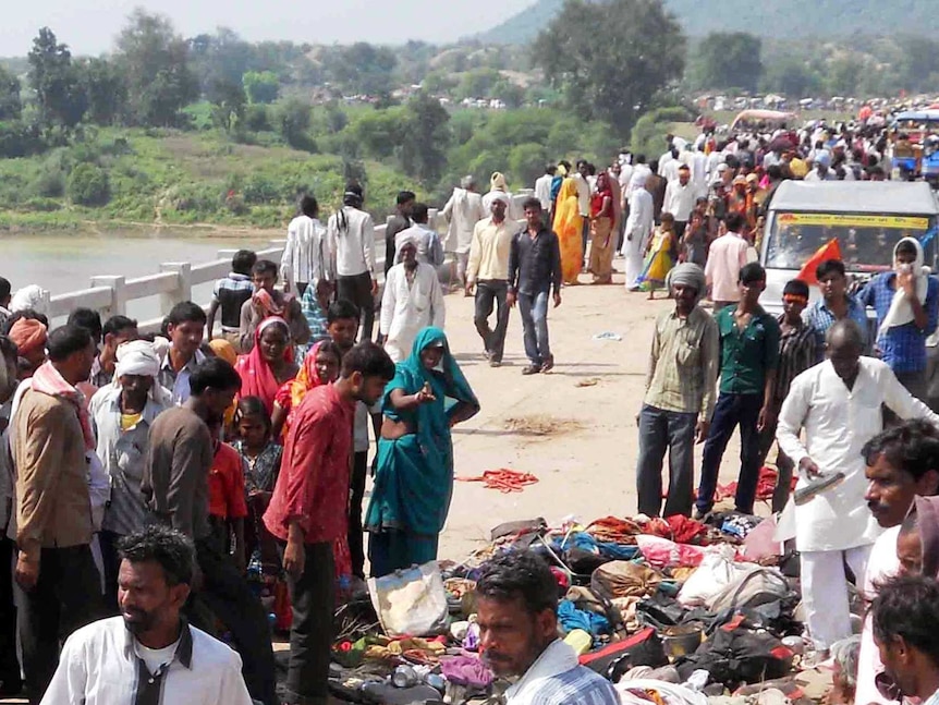 Pilgrims gather at the site of a stampede and bridge collapse in India