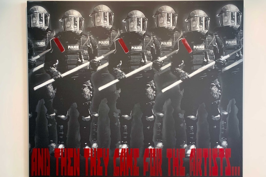 Photo of a piece of art with police officers holding paint rollers with red ends.