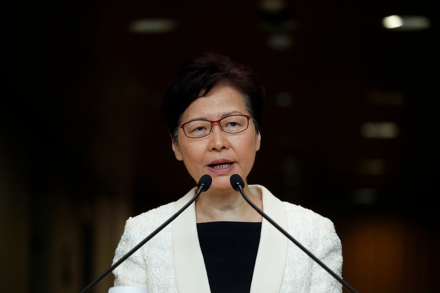 Carrie Lam speaks into two microphones on a lectern.