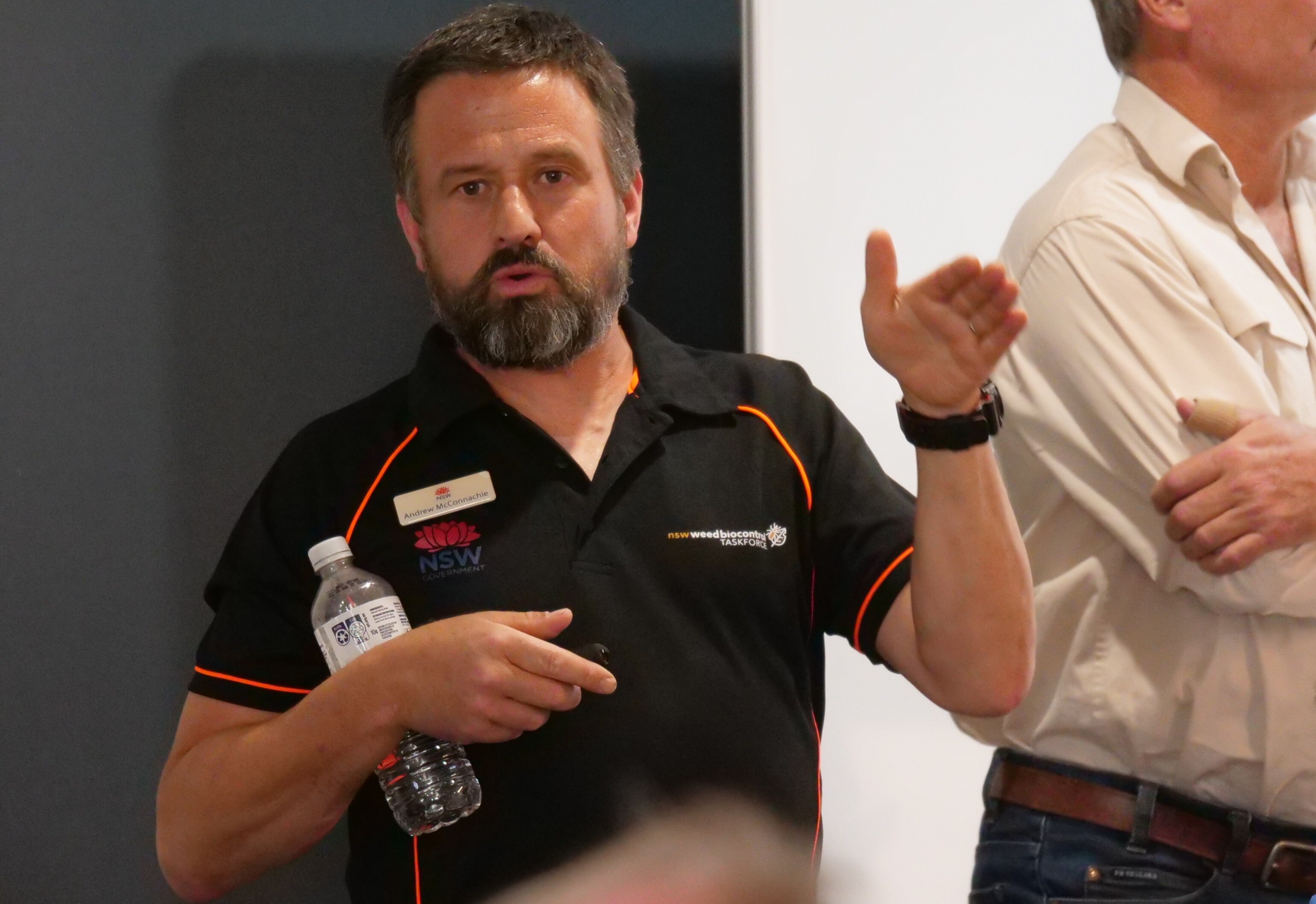 homem de camisa preta e barba fala e gesticula com o braço