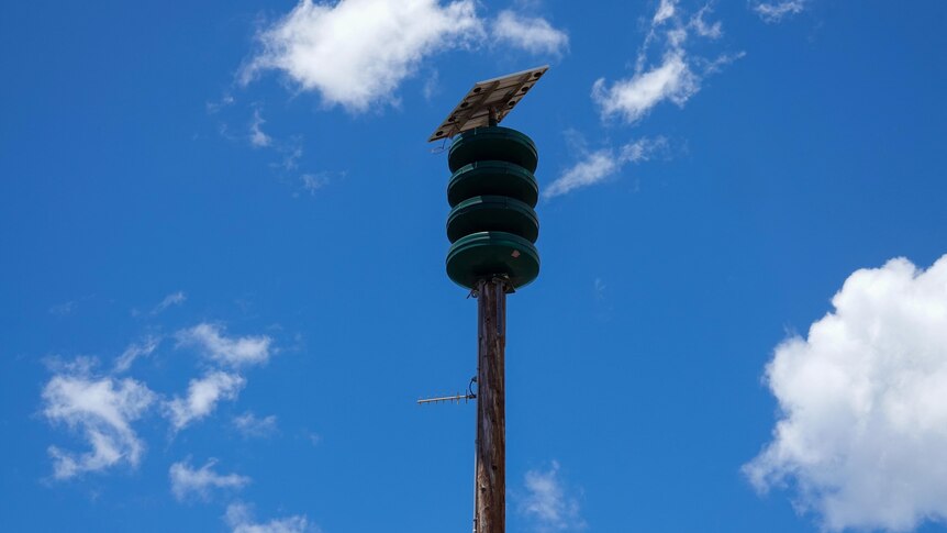 A pole with a device on top of it, made up of four discs and a small solar panel, visibly burnt by fire