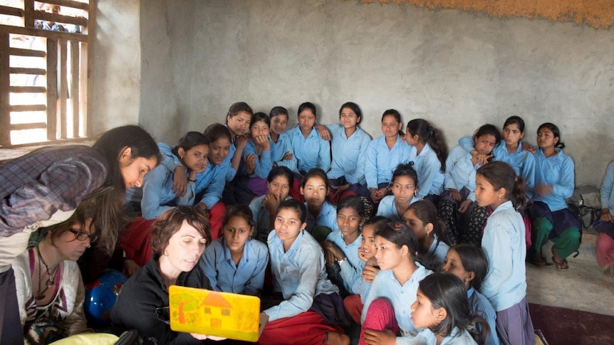 School girls sit before an educator with a laptop