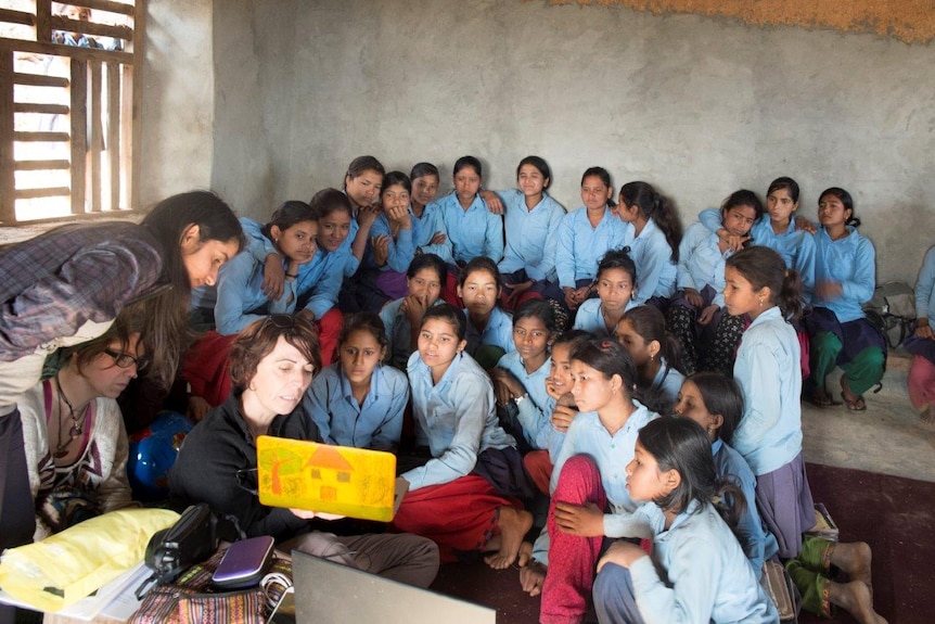 School girls sit before an educator with a laptop