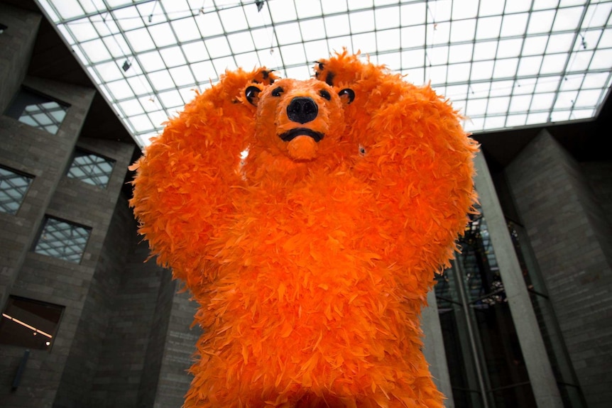 A sculpture of an orange neon feathered bear