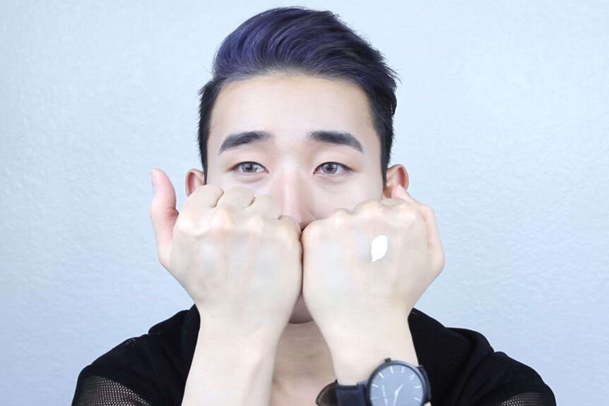 Ivan Lam demonstrates using skin whitening cream in a video posted on YouTube.