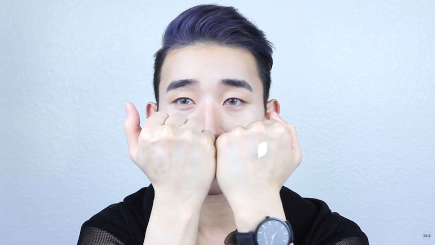 Ivan Lam demonstrates using skin whitening cream in a video posted on YouTube.