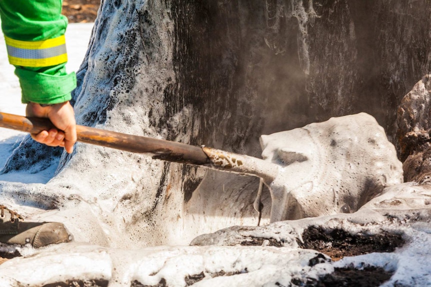 Andy Beckett digs out the burning embers inside the tree with a shovel.