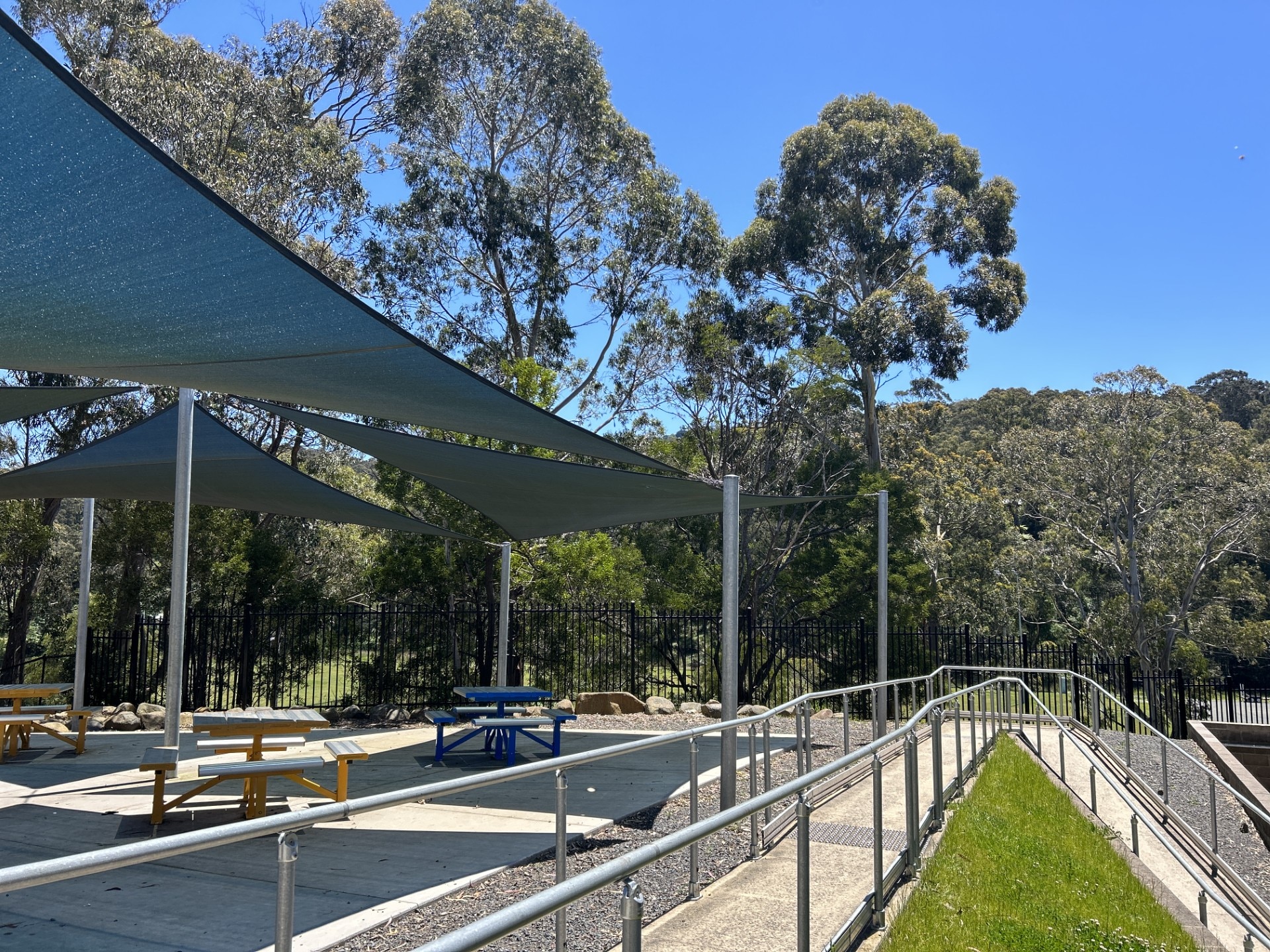 Patio de la escuela con sombrillas y mesas de picnic.