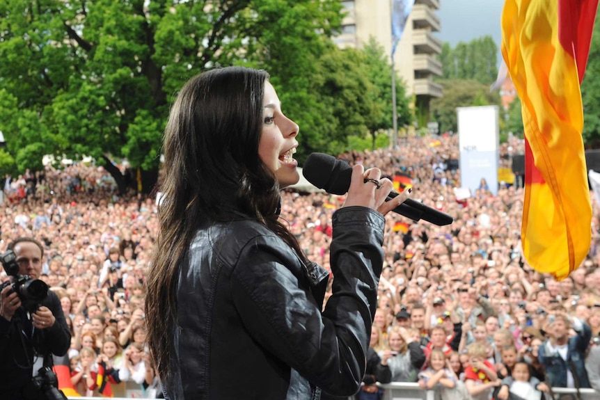 A performer sings as thousands of fans watch on at a Eurovision homecoming reception.