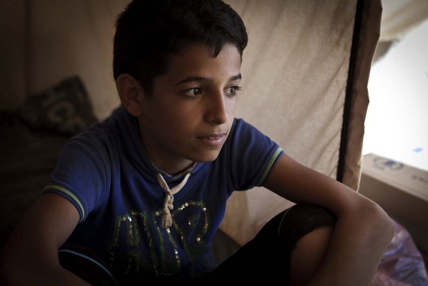 Boy sits in tent in Za'atari refugee camp in Jordan