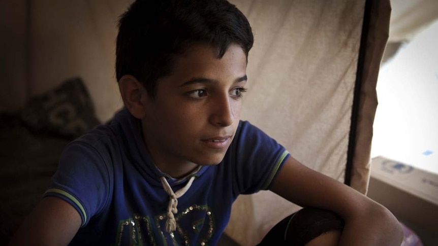 Boy sits in tent in Za'atari refugee camp in Jordan