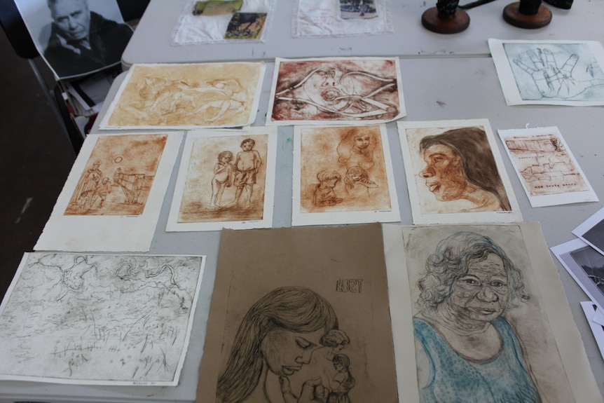 Photo of art work on a table, including sketches of women.