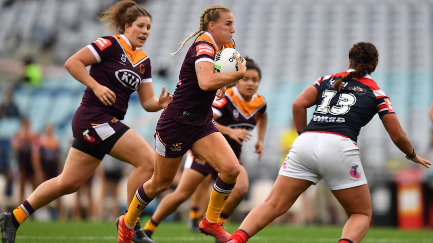 A player tucks the ball under her arm as she runs toward the tryline in an NRLW game.