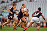 A player tucks the ball under her arm as she runs toward the tryline in an NRLW game.