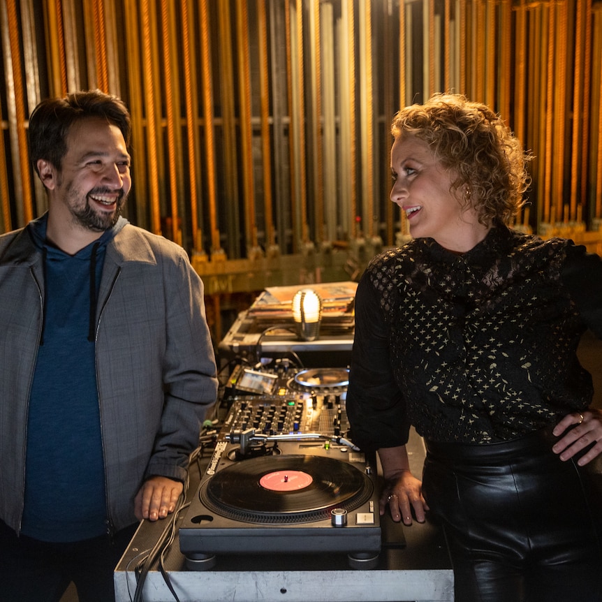 Lin-Manuel Miranda and Zan Rowe stood either side of a record player smiling at each other