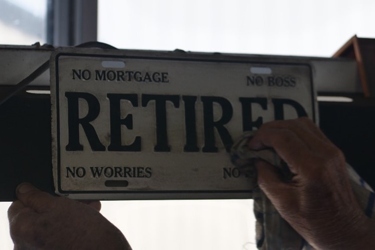 A hand cleans a sign which reads Retired, No Mortgage, No Boss, No Worries