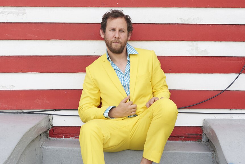 Musician Ben Lee sits in a bright yellow suit.