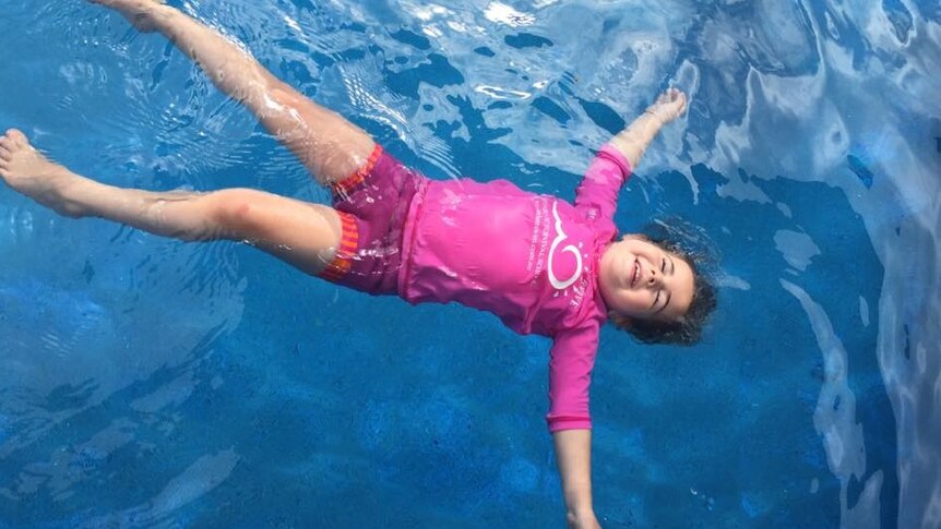 A child floats on her back in a pool.