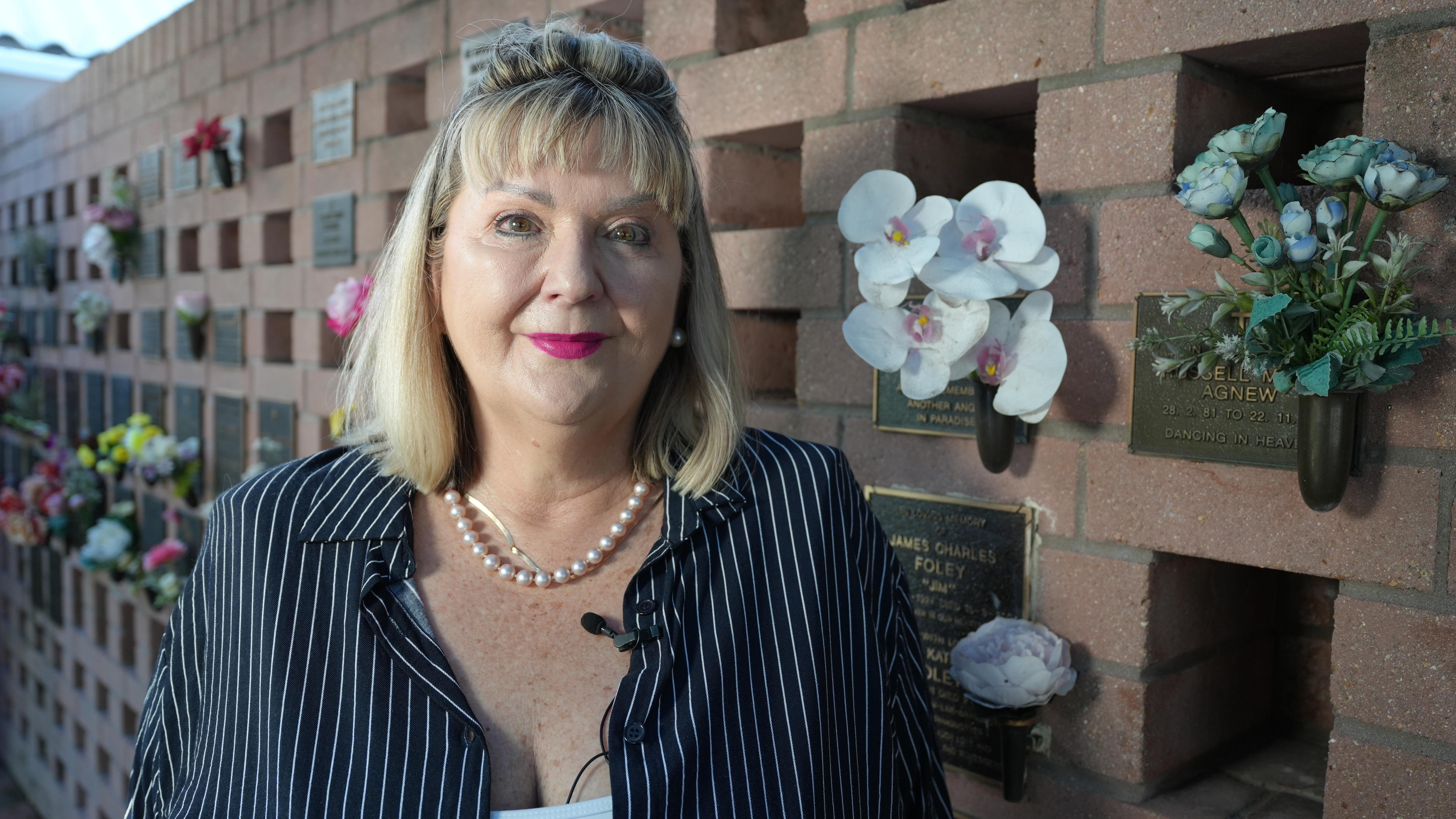 A woman stands in front of a columbarium